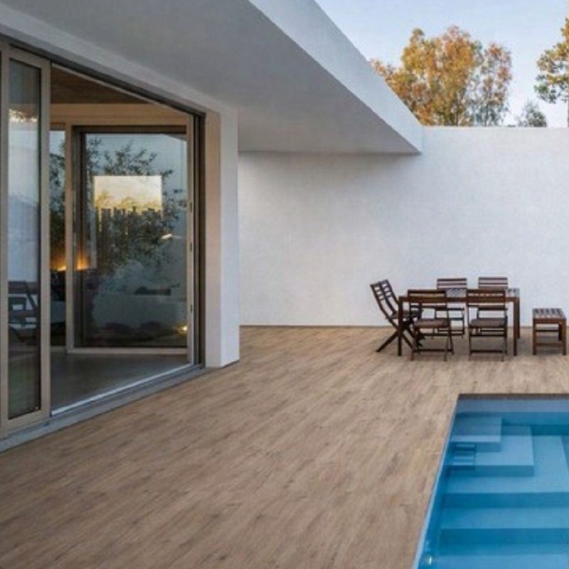 Wood look porcelain paver pool deck beside a modern white house